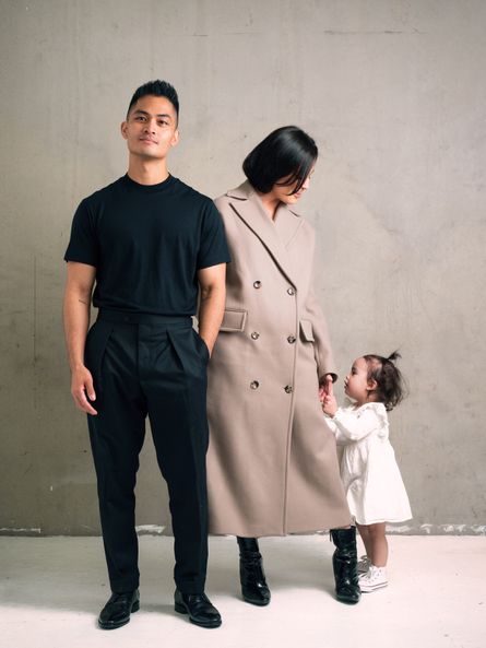 Roland standing to the right of his wife Elle with their daughter holding Elle's hand